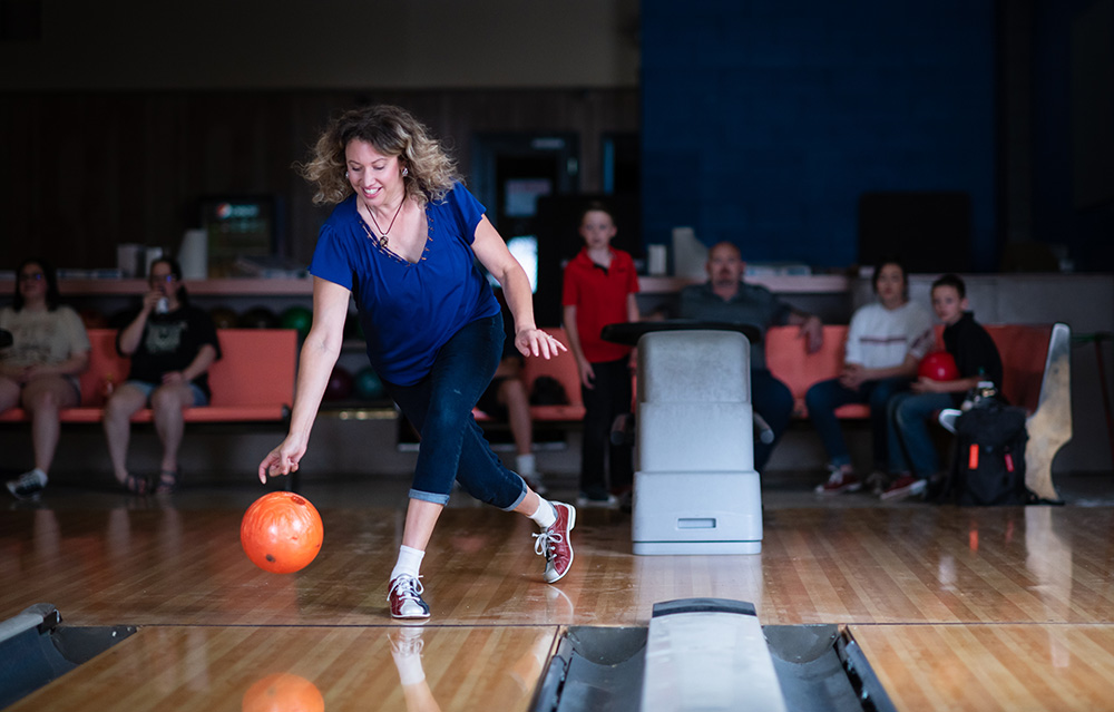 Woman bowling with friends watching behind